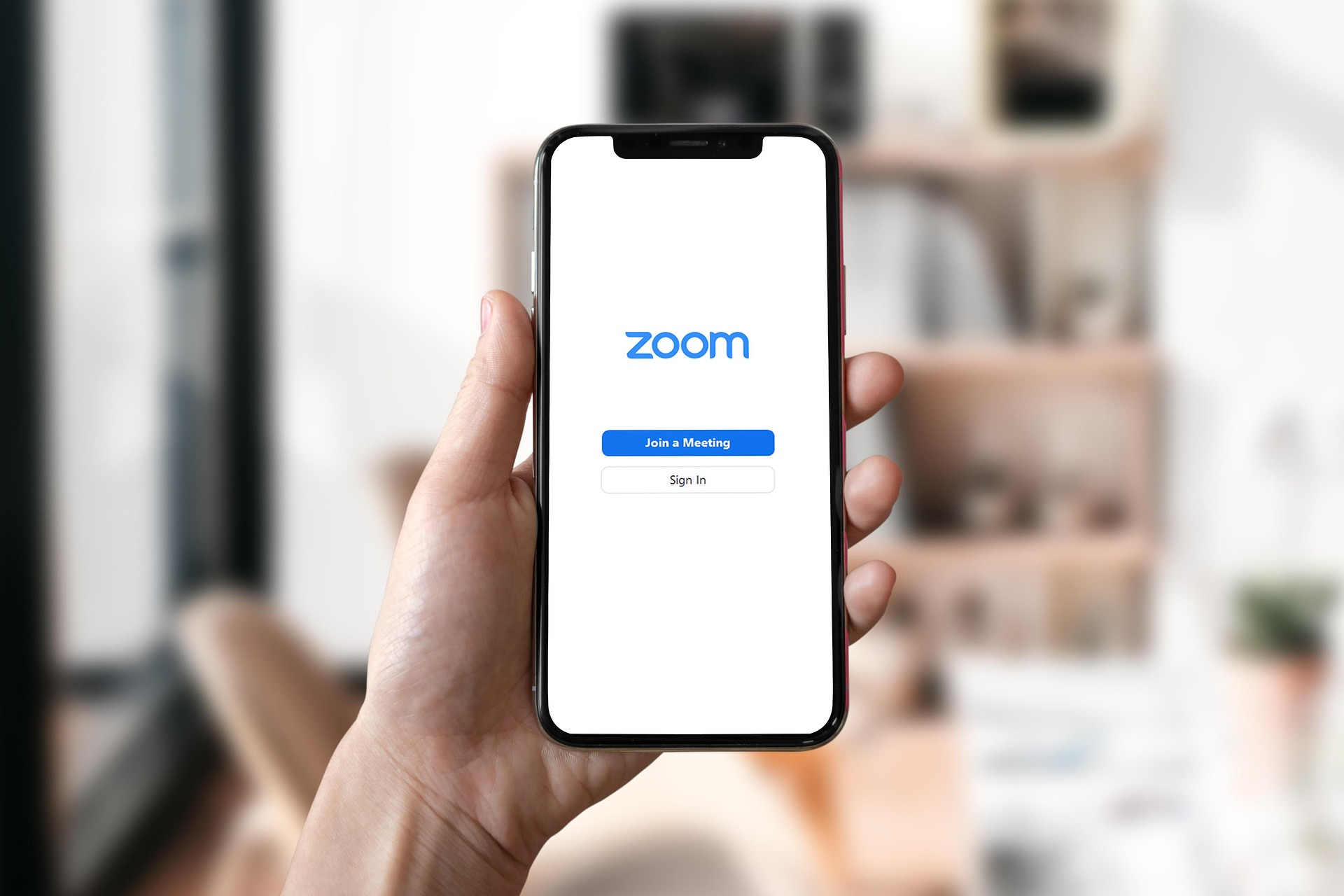 Hand holding smartphone with Zoom app open showing Join a Meeting screen
